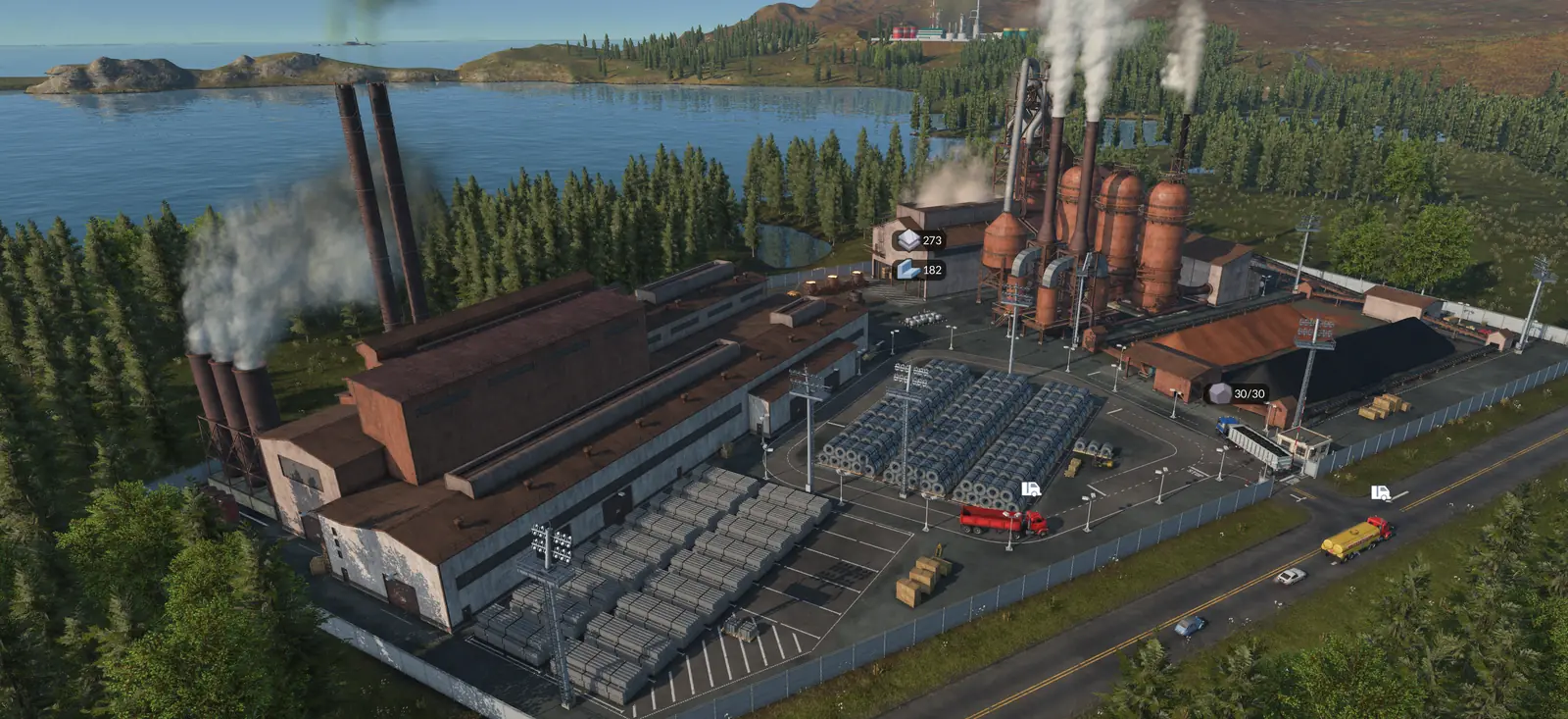 A Transport Fever 3 steel mill by a lake among pine forests, with smoking chimneys, blast furnaces, stacks of steel and trucks on the road outside
